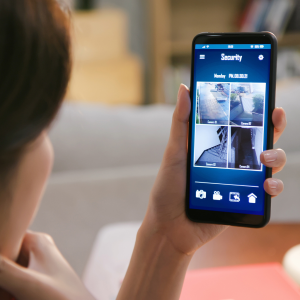 homeowner monitoring security cameras via her smartphone